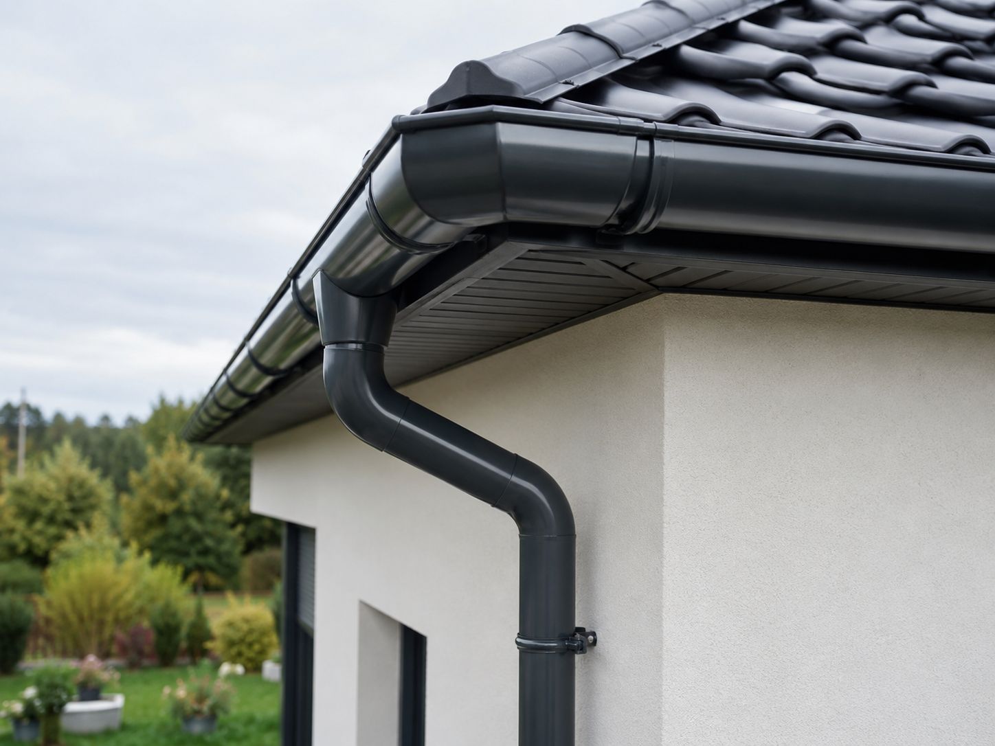 Ciemny system rynnowy z rurą spustową zamontowany przy dachu domu